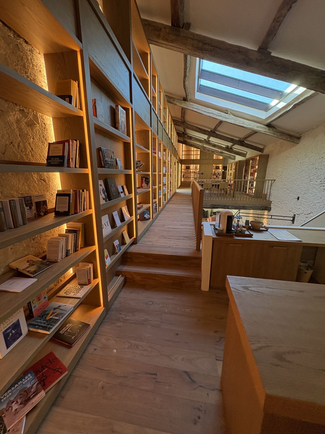 Une grande bibliothèque sur mesure, rayonnages en bois le long d’une galerie