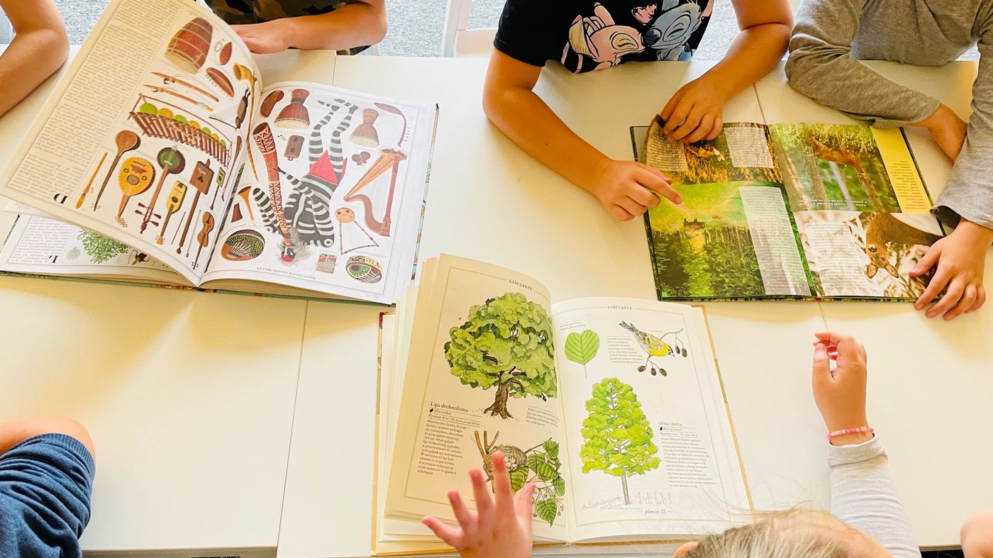 Des mains d’enfants autour de livres illustrés ouverts sur une table
