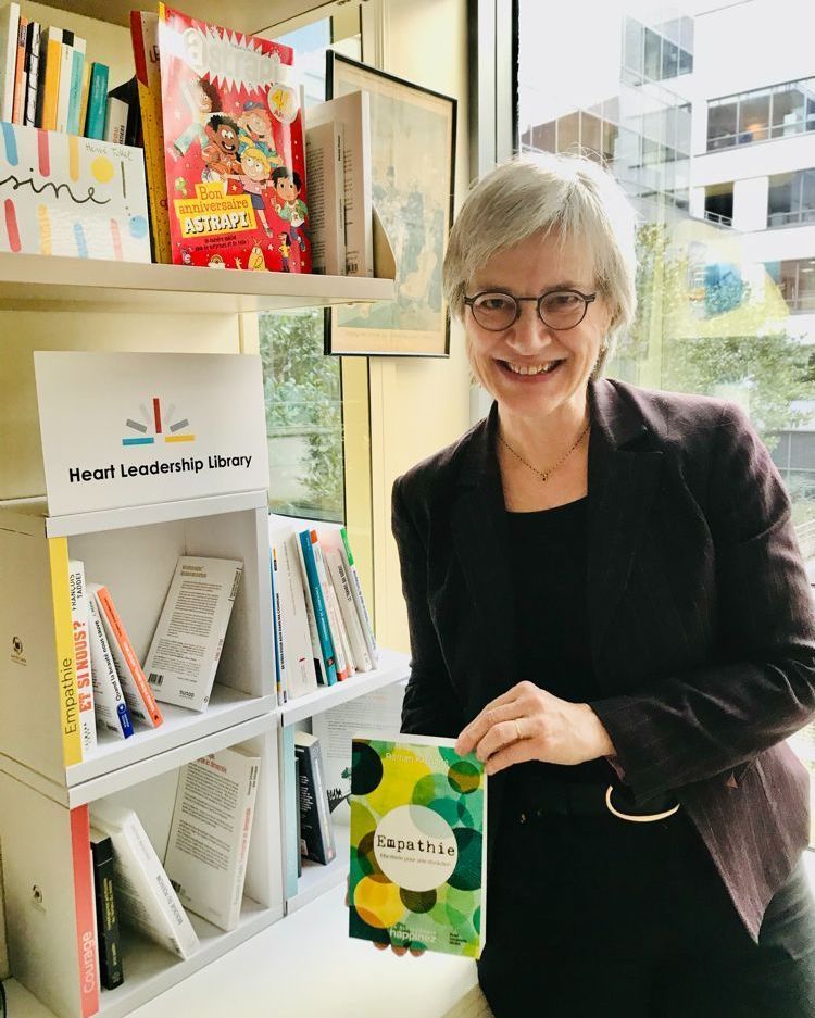 Une lectrice présente un livre devant une bibliothèque installée en entreprise