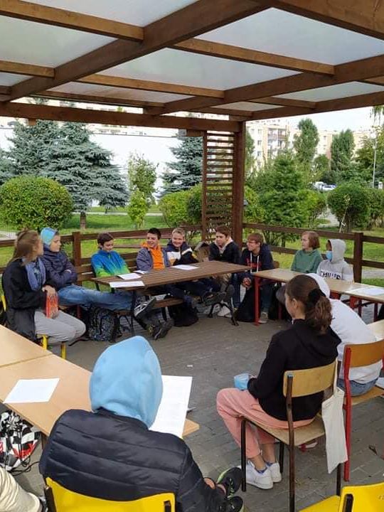 Un atelier de lecture en cercle, sous une pergola